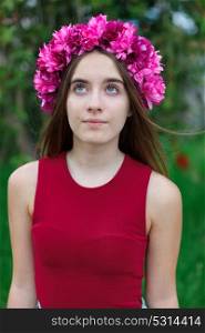 Cute teenager girl in a park with a beautiful wreath on her head