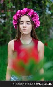 Cute teenager girl in a park with a beautiful wreath on her head