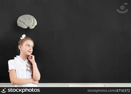 Cute thoughtful school girl and brain above her head. Let me think