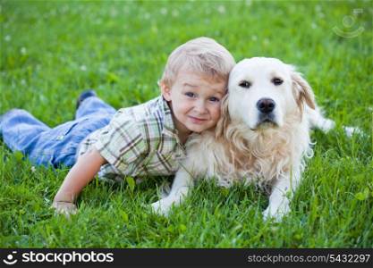 Cute toddler blonde boy with golden retriever hugging close up