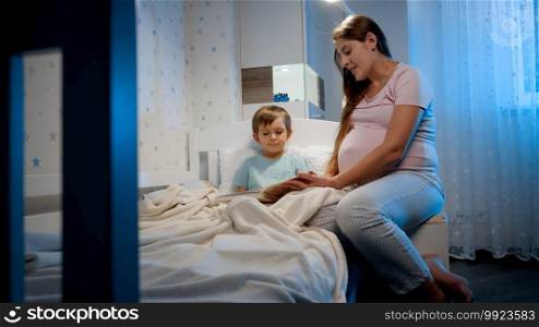 Cute toddler boy listening to fairy tale book his pregnant mother is reading before going to sleep at night. Parenting and child education.. Cute toddler boy listening to fairy tale book his pregnant mother is reading before going to sleep at night. Parenting and child education
