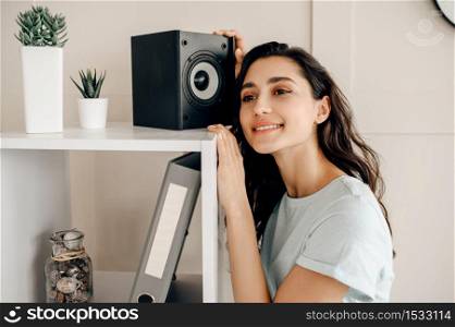 Cute woman against audio speaker listen to music. Pretty lady relax in the room, female sound lover resting. Cute woman against audio speaker listen to music