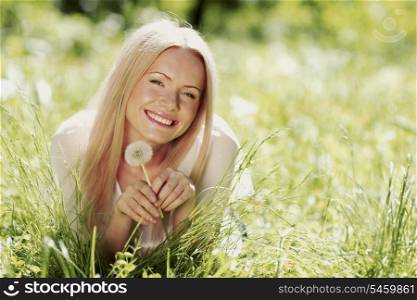 Cute woman lay in the park with dandelions