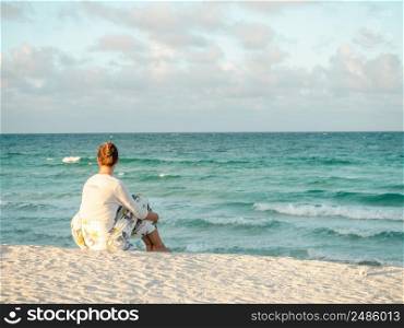 Cute woman on the beach against the background of the sea, looking into the distance. Outdoors, closeup. Concept of leisure and travel. Cute woman on the beach against the background of the sea
