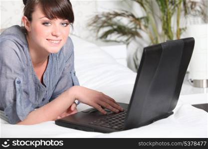 Cute woman using a laptop on her bed