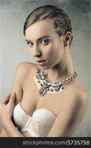 cute woman with creative plait hairdo, starry shiny make-up and stylish necklace, white bra, in sensual pose