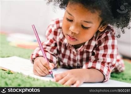 Cute young African American kid girl drawing or painting with colored pencil. Kindergarten children education, back to school, or preschool child study at home concept