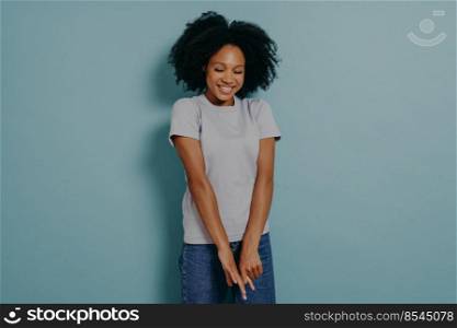 Cute young african lady wearing casual outfit looking down with with shy timid face expression, shrugging shoulders and feeling embarrassed with uncomfortable question, isolated over blue background. Young african lady looking down with with shy timid face expression, isolated over blue background