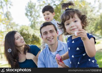 Cute Young Baby Girl Blowing Bubbles with Her Family in the Park.