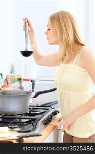 cute young blond woman cooking at kitchen