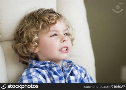 Cute Young Blonde Boy Daydreaming and Sitting in Chair.