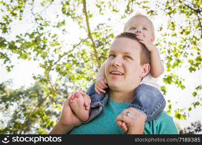 Cute Young Boy Rides Piggyback On His Dads Shoulders Outside at the Park.