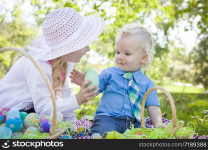 Cute Young Brother and Sister Enjoying Their Easter Eggs Outside in the Park Together.