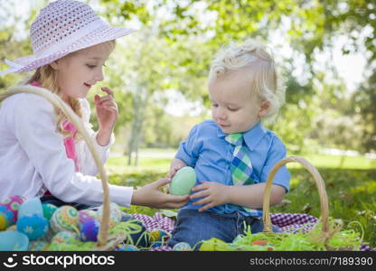 Cute Young Brother and Sister Enjoying Their Easter Eggs Outside in the Park Together.