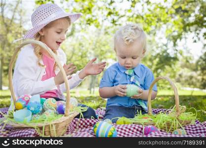Cute Young Brother and Sister Enjoying Their Easter Eggs Outside in the Park Together.
