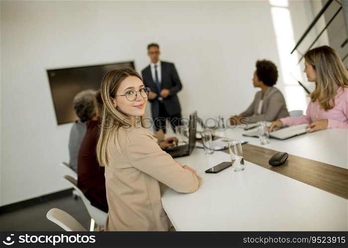 Cute young business woman sitting by the table with colleagues while working on new project
