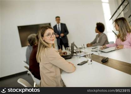 Cute young business woman sitting by the table with colleagues while working on new project