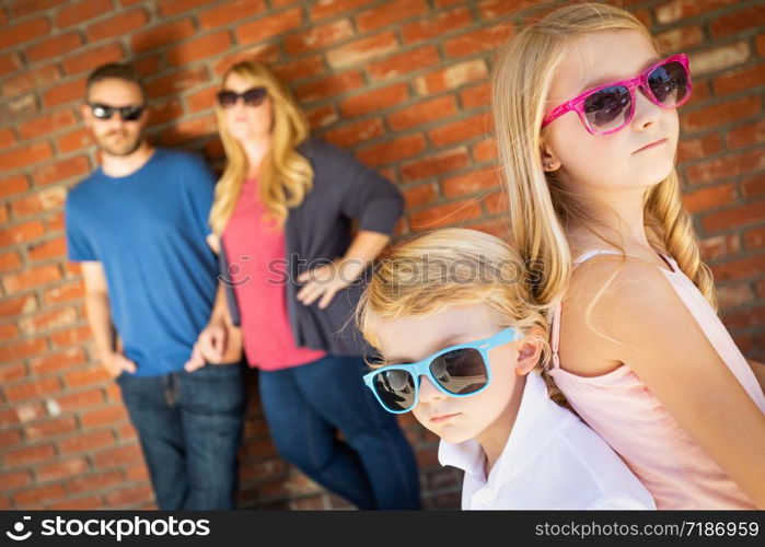 Cute Young Caucasian Brother And Sister Wearing Sunglasses with Parents Behind.