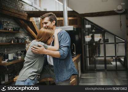 Cute young couple hugging while cooking in their apartment kitchen