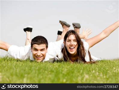cute young Couple lie down on grass in a hands outstretched