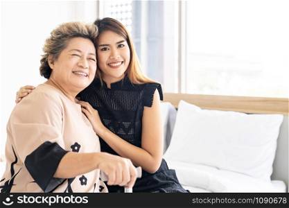 Cute young daughter embracing hug her happy old elderly mother with love at home
