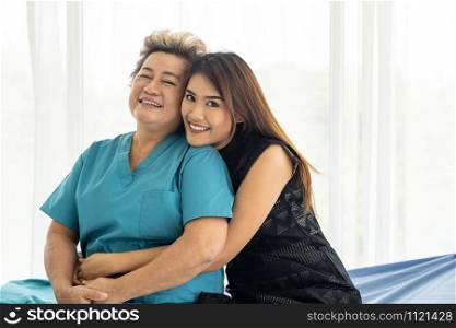 Cute young daughter embracing hug her happy old elderly mother with love at home