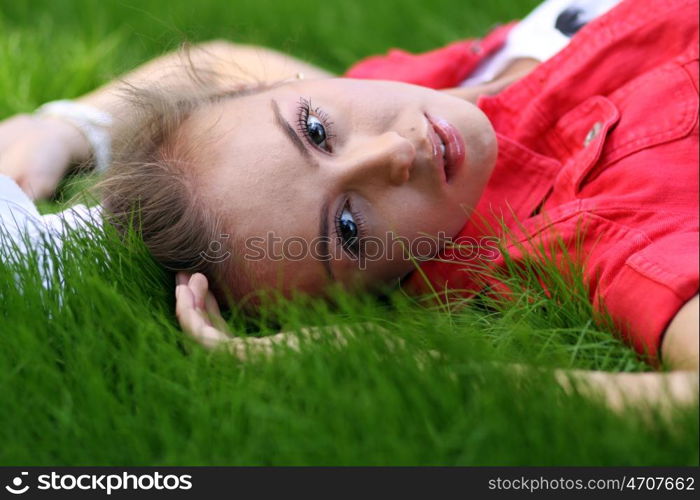 Cute young female lying on grass field at the park