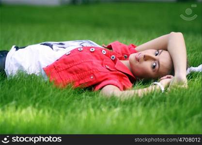 Cute young female lying on grass field at the park