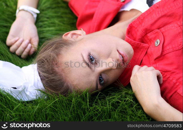 Cute young female lying on grass field at the park