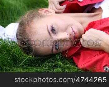 Cute young female lying on grass field at the park
