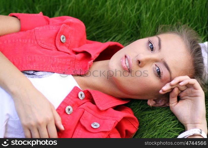 Cute young female lying on grass field at the park