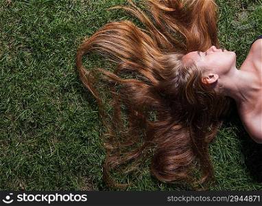 Cute young female lying on grass field at the park . Woman relaxes on the grass. Cute young female lying on grass field at the park.