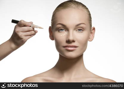 cute young female posing in beauty portrait with perfect skin and smiling. Applying cosmetics on her visage for the make-up