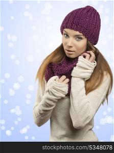 cute young girl posing with winter dress in fashion shot. She looking in camera and wearing purple wool hat, scarf and warm white sweater