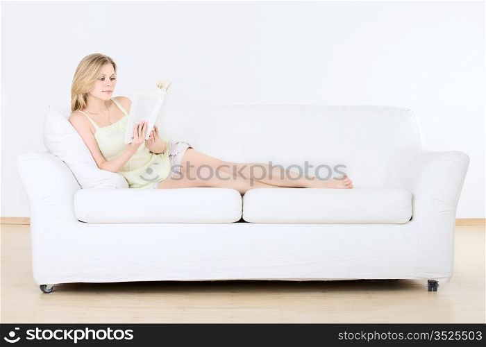 cute young girl reading on couch at home