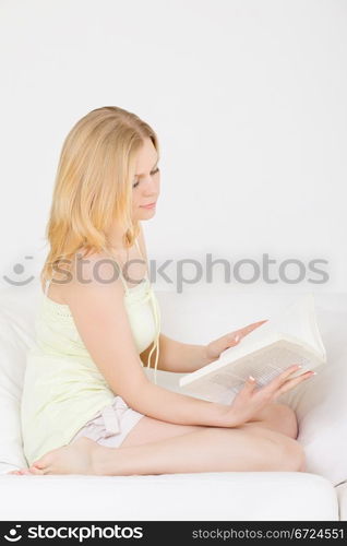 cute young girl reading on couch at home