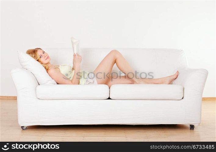 cute young girl reading on couch at home