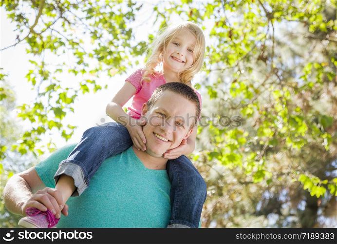 Cute Young Girl Rides Piggyback On Her Dads Shoulders Outside at the Park.