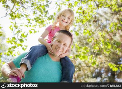Cute Young Girl Rides Piggyback On Her Dads Shoulders Outside at the Park.