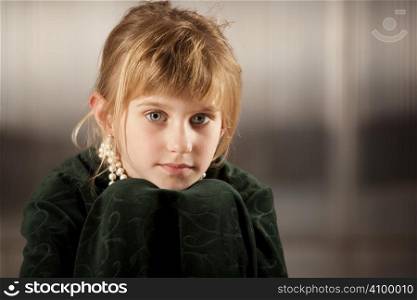 Cute young girl with big eyes in dress-up clothes chin on knees