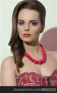 cute young girl with elegant smooth brown hairstyle, summer make-up and red necklace, wearing fashion dress