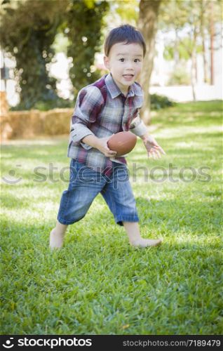 Cute Young Mixed Race Boy Playing Football Outside At The Park.