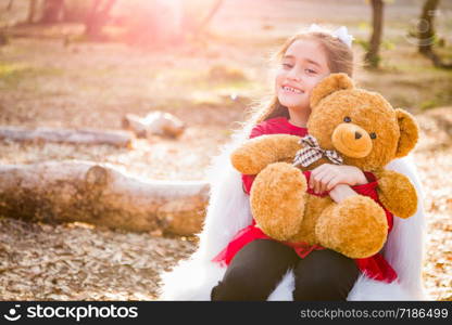 Cute Young Mixed Race Girl Hugging Teddy Bear Outdoors.