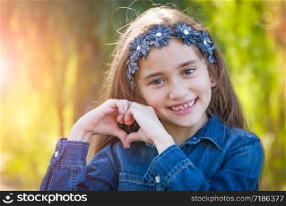 Cute Young Mixed Race Girl Making Heart Hand Sign Outdoors.