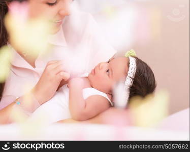 Cute young mother looking on sweet newborn daughter, take care about her, photo with soft focus, happy motherhood concept