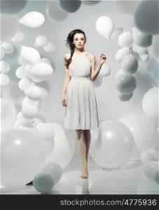 Cute young woman among numerous white balloons