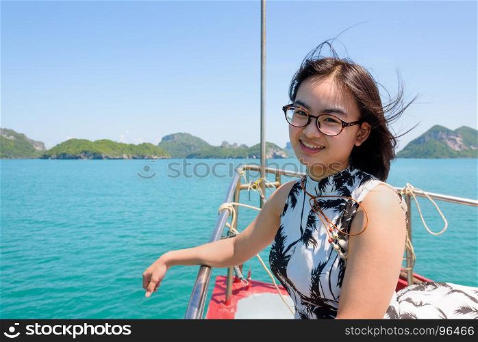 Cute young woman on the prow. Cute young woman with eyeglasses smiling happily on the prow boat while cruising the beautiful natural of the blue sea and sky in summer at Mu Ko Ang Thong National Park, Surat Thani, Thailand