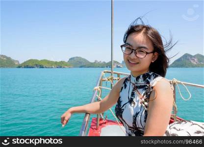 Cute young woman on the prow. Cute young woman with eyeglasses smiling happily on the prow boat while cruising the beautiful natural of the blue sea and sky in summer at Mu Ko Ang Thong National Park, Surat Thani, Thailand