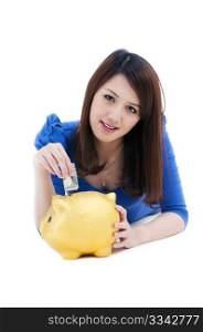 Cute young woman putting money into piggy bank over white background