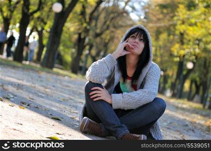 Cute young woman sitting outdoors in nature